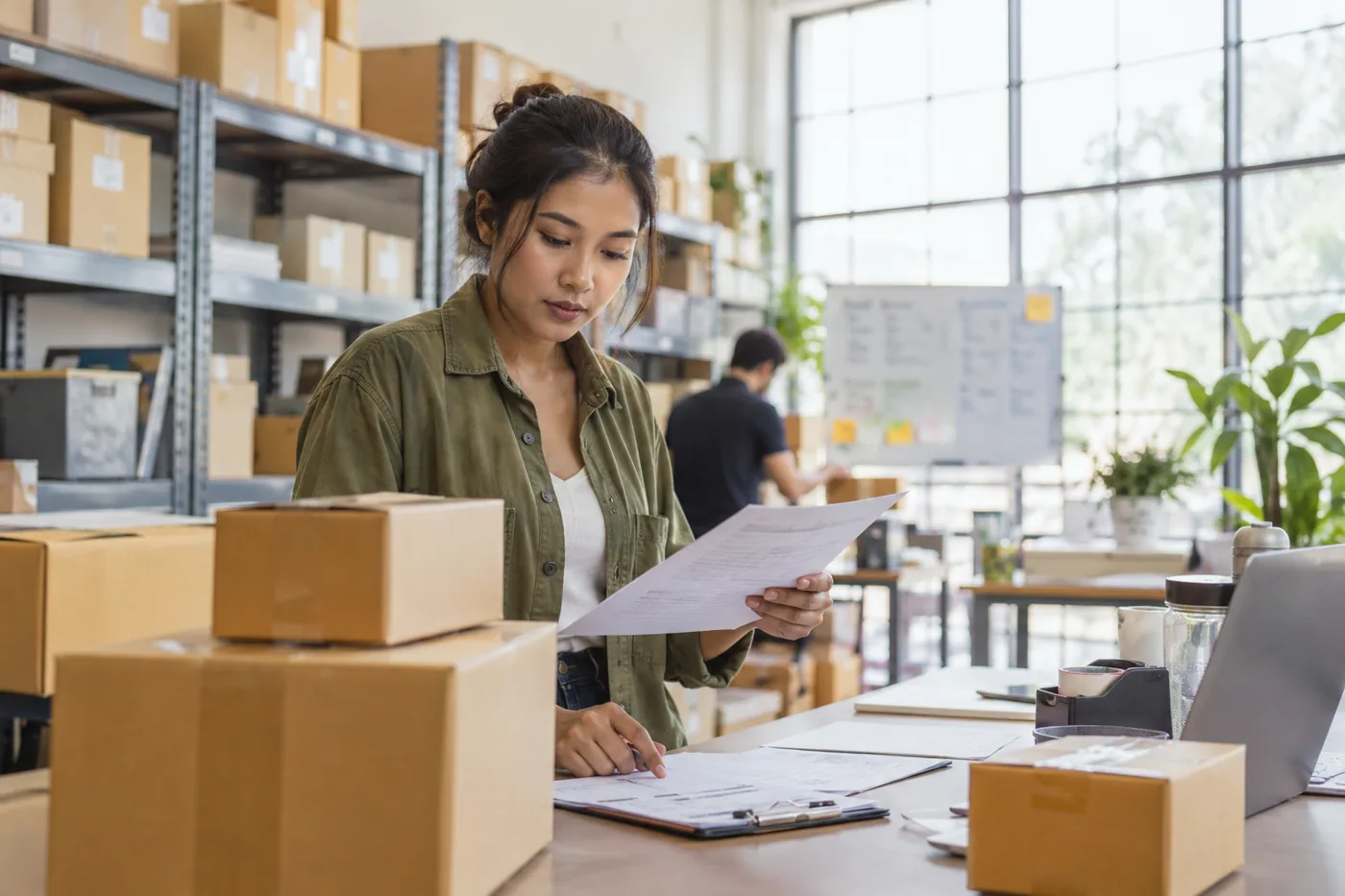 Illustrative scene: Ecommerce administrator reviewing paperwork beside unbranded parcels