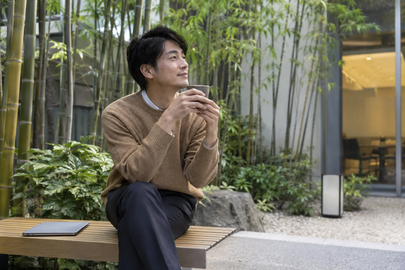 Illustrative scene: Office worker taking a tea break with a closed laptop in a courtyard