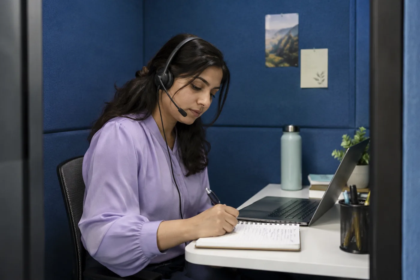 Illustrative scene: Support specialist using a headset and taking handwritten call notes